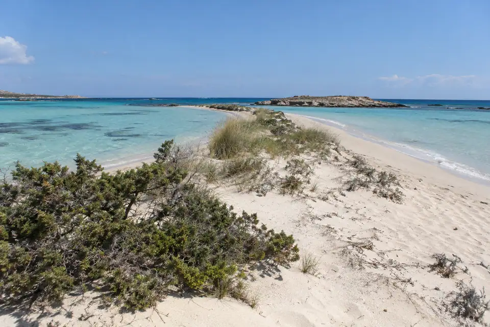 Smalle lage zandbank met zeer ondiep turquoise water aan beide zijden, kleine duinen, geen bebouwing.