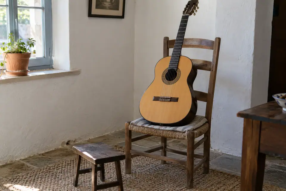 Klassieke gitaar met lichte bovenkant en ingelegde mozaïekrand rond het klankgat op een houten stoel.