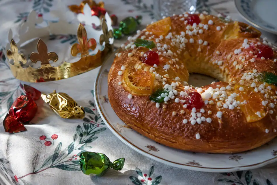 Ringvormig zoet brood met gekonfijte vruchten en perlesuiker, naast een gouden papieren kroon.
